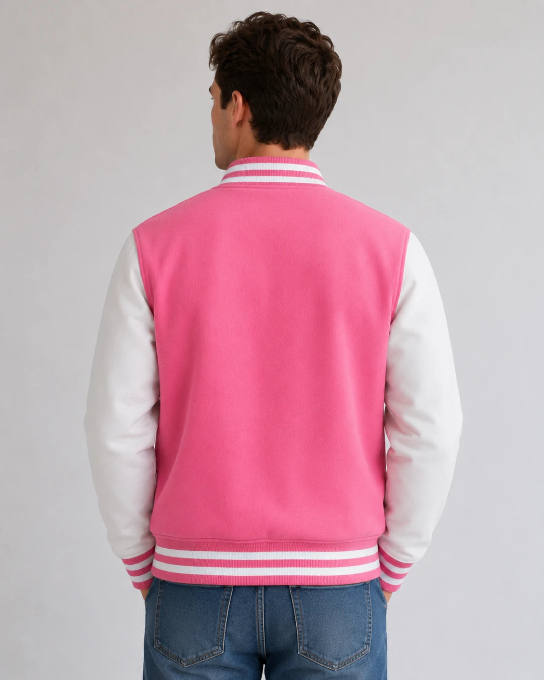 Back view of mens pink and white varsity jacket with blank pink wool body, white leather sleeves, and striped ribbed hem on male model