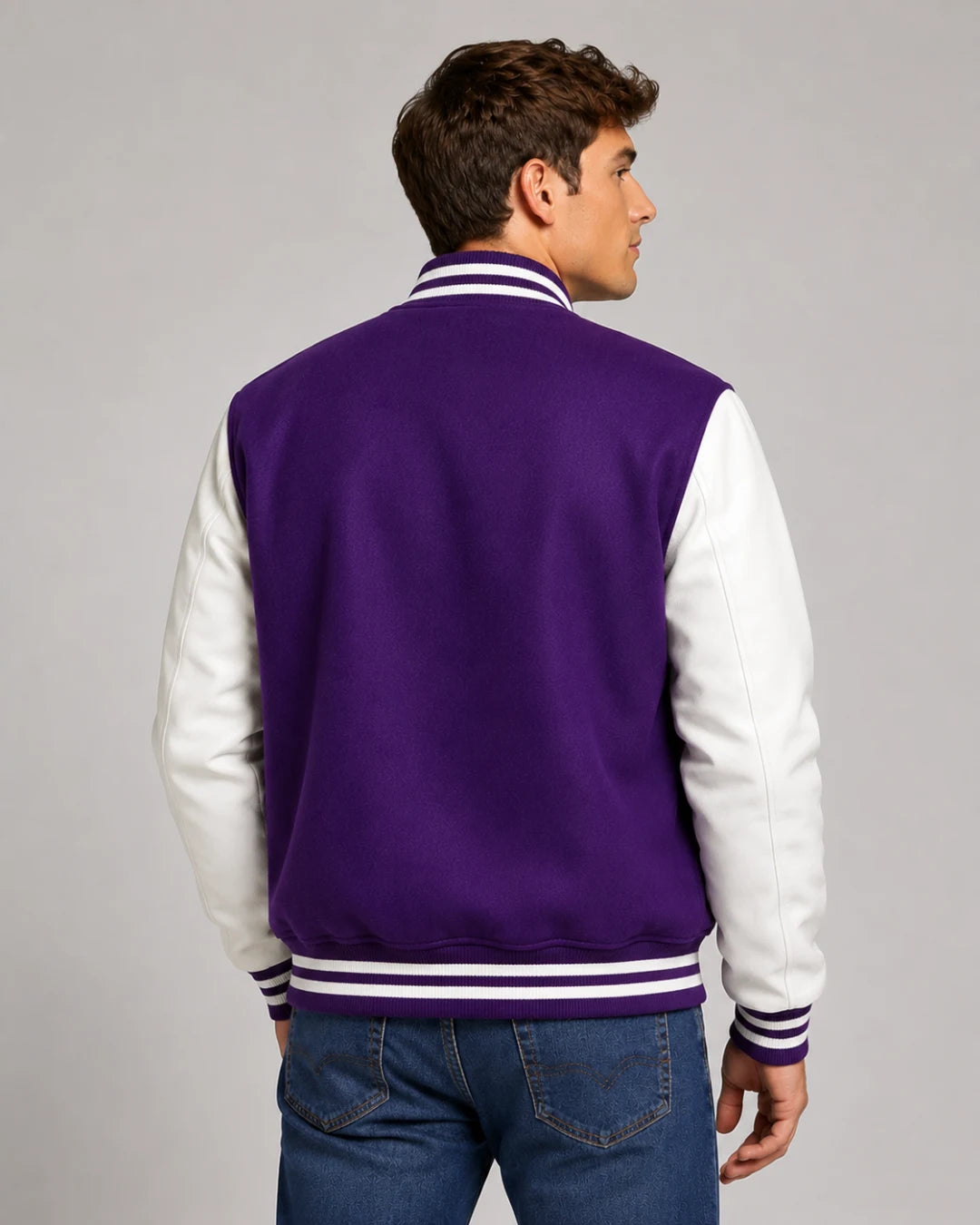 Back view of mens purple varsity jacket with blank wool body, white leather sleeves, and striped ribbed hem on male model