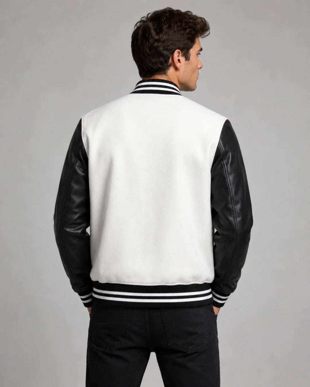 Back view of mens white and black varsity jacket with blank white wool body, black leather sleeves, and striped ribbed hem on male model
