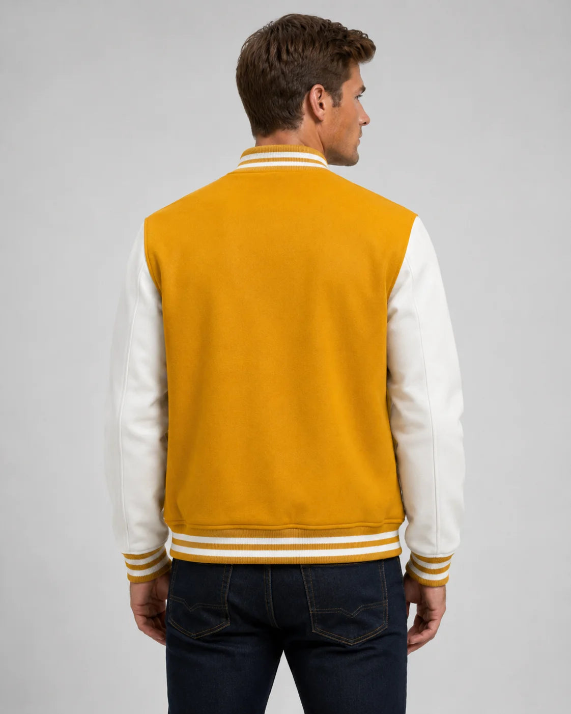 Back view of mens yellow and white varsity jacket with blank yellow wool body, white leather sleeves, and striped ribbed hem on male model