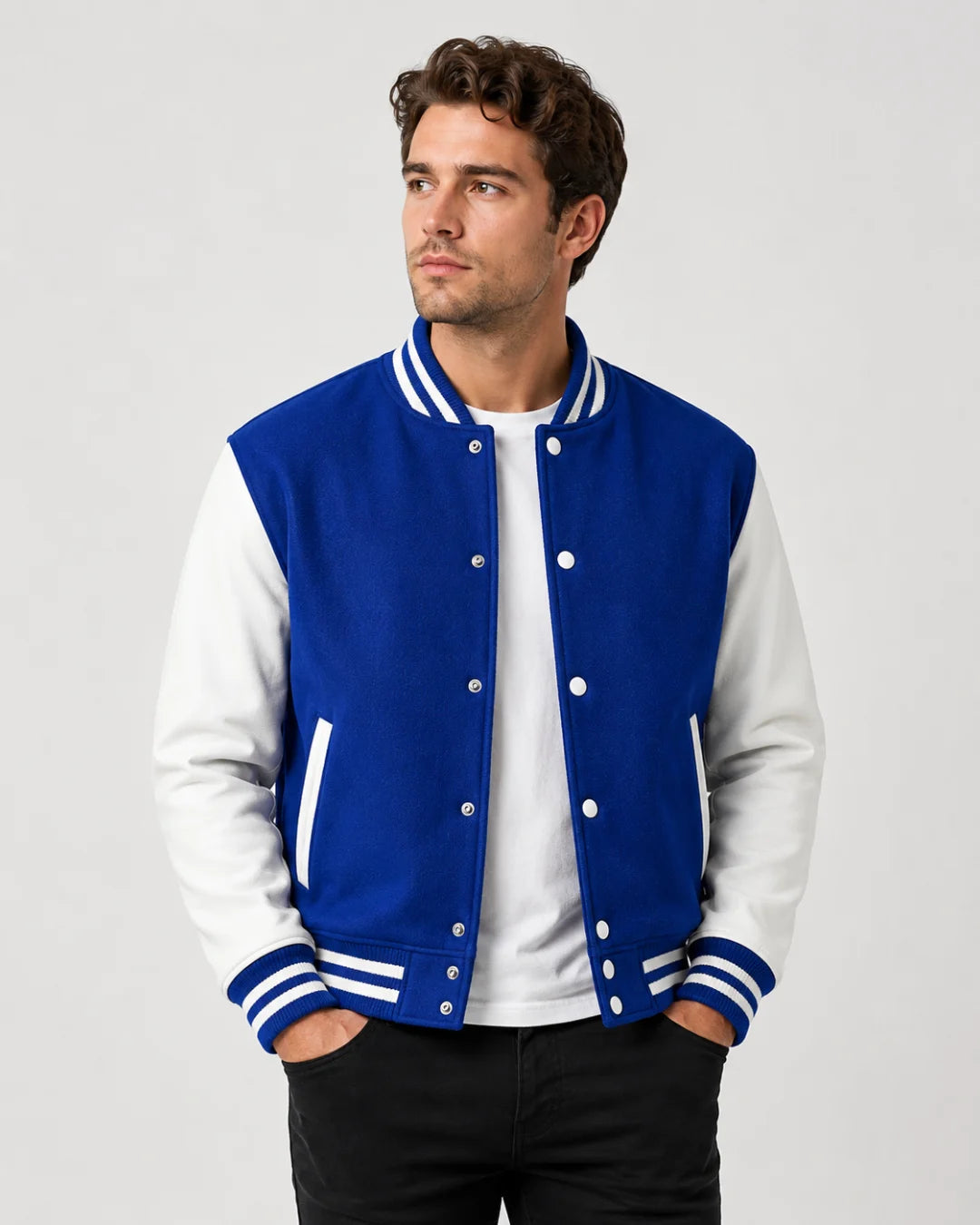 Mens blue varsity jacket with wool body, white leather sleeves, snap buttons, and striped ribbed trim worn by male model