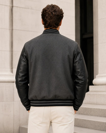 Back view of a blank men's black and grey varsity jacket with black leather sleeves
