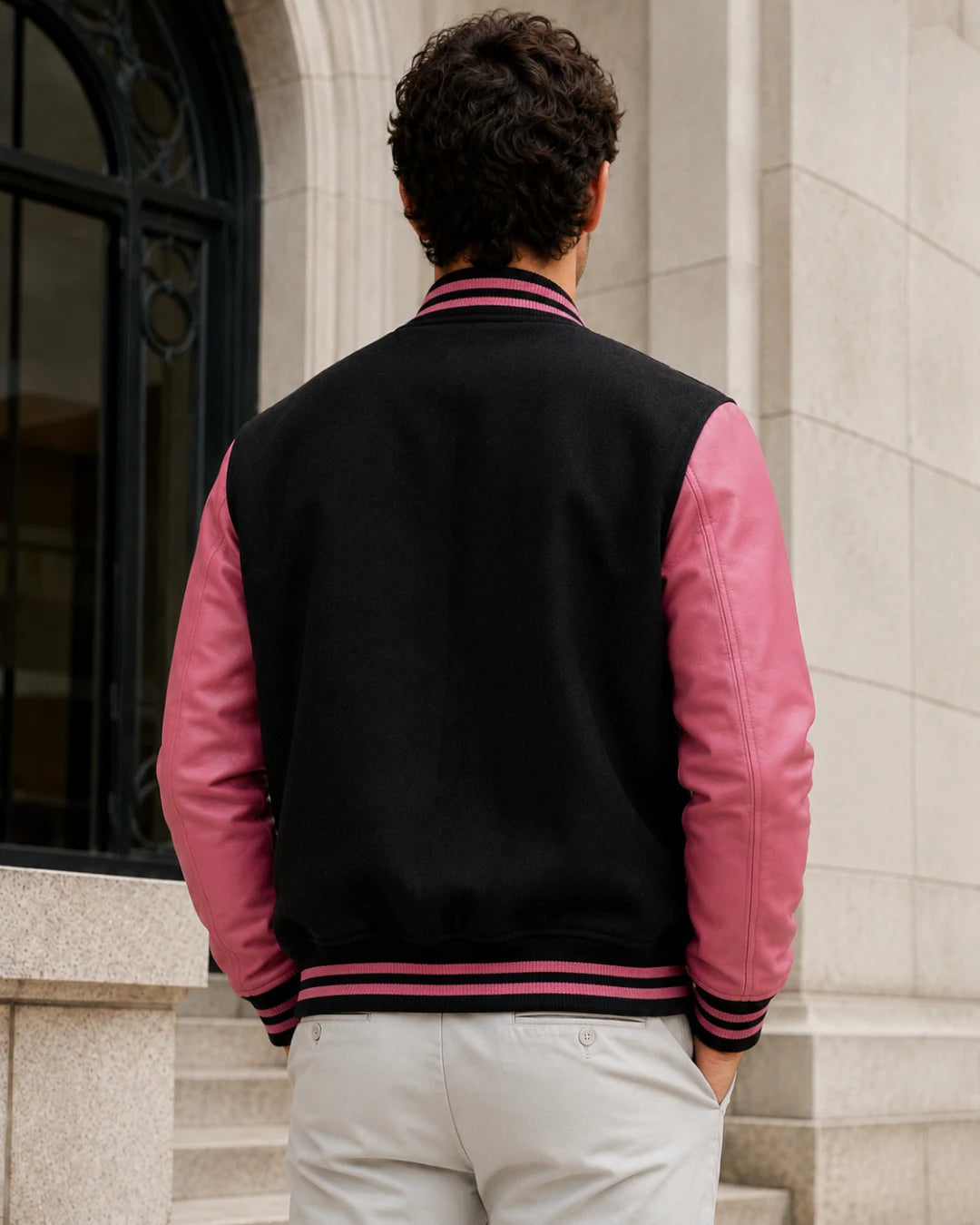 Back view of a blank men's black and pink varsity jacket with rose-pink leather sleeves