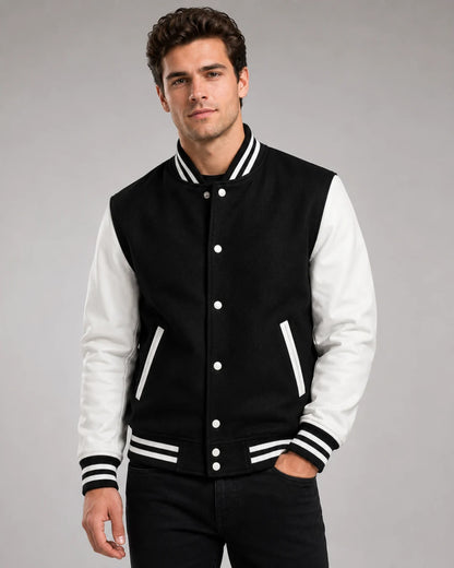 Mens black and white varsity jacket with wool body, white leather sleeves, snap buttons, and striped ribbed trim worn by male model