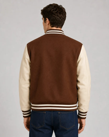 Back view of mens brown varsity jacket with blank brown wool body, cream leather sleeves, and striped ribbed hem on male model