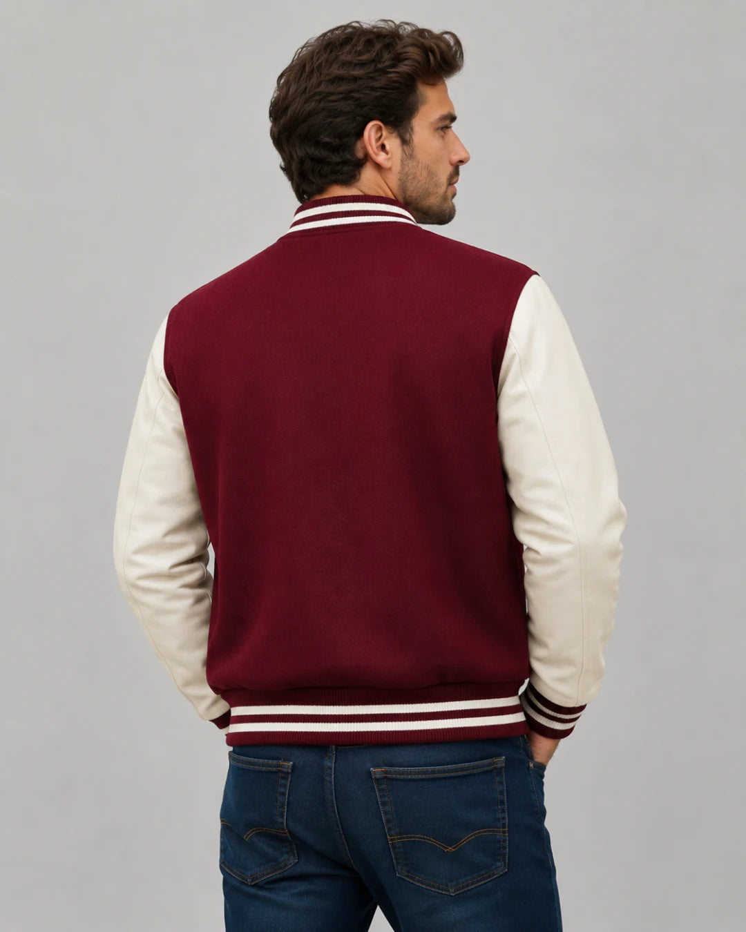 Back view of mens burgundy varsity jacket with blank burgundy wool body, cream leather sleeves, and striped ribbed hem on male model