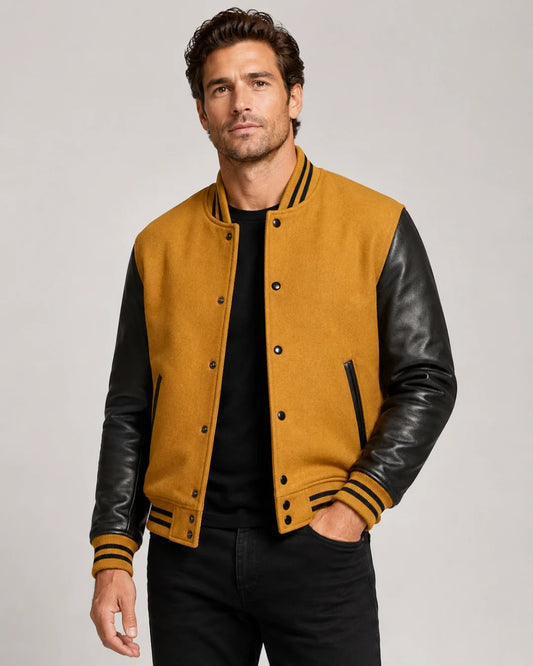 American male model wearing a men's gold varsity jacket with black leather sleeves, front view