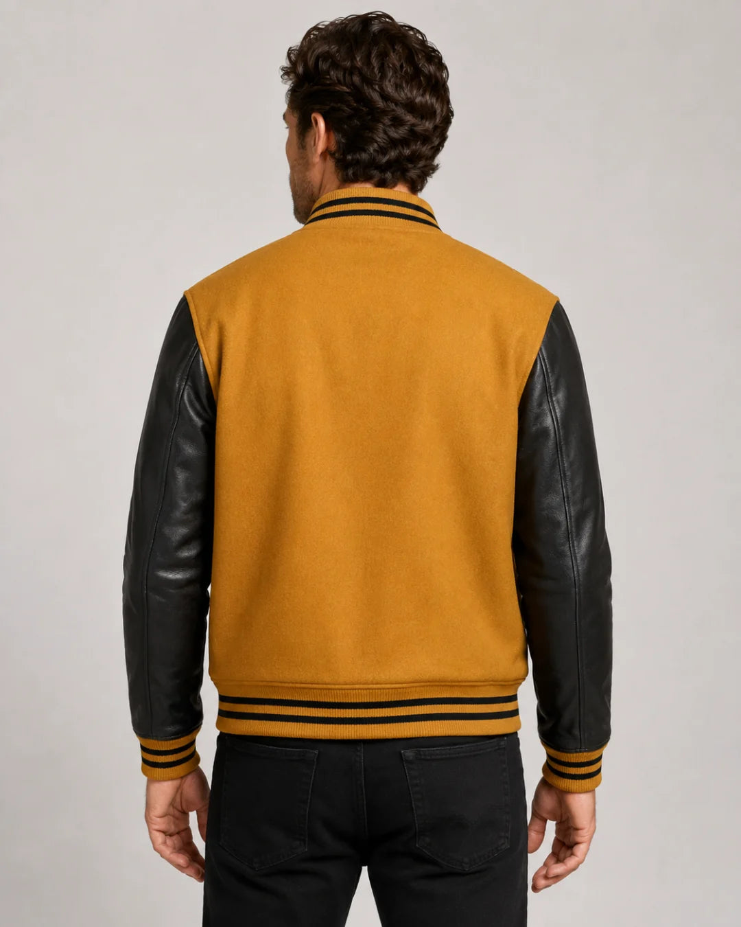 Back view of a men's gold varsity jacket with an antique-gold wool body and black leather sleeves