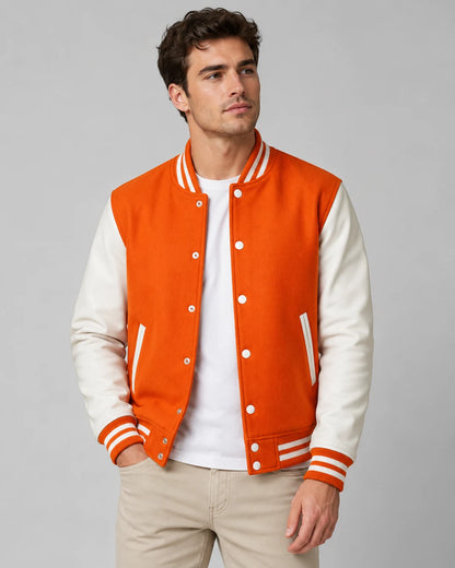 Mens orange varsity jacket with wool body, white leather sleeves, snap buttons, and striped ribbed trim worn by male model