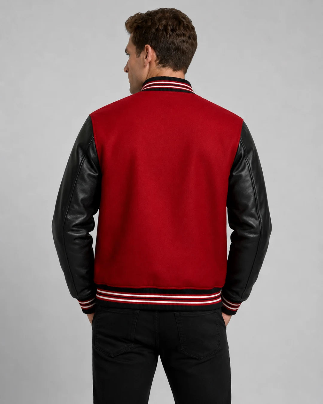 Back view of mens red and black varsity jacket with blank red wool body, black leather sleeves, and striped ribbed hem on male model