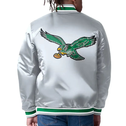 White jacket with green eagle logo on the back, worn by a person.