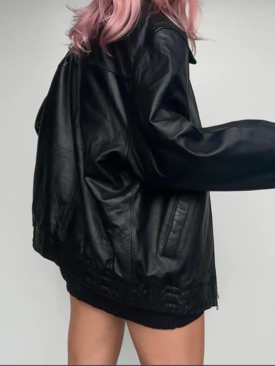 Person wearing a black leather jacket with pink hair on a plain background